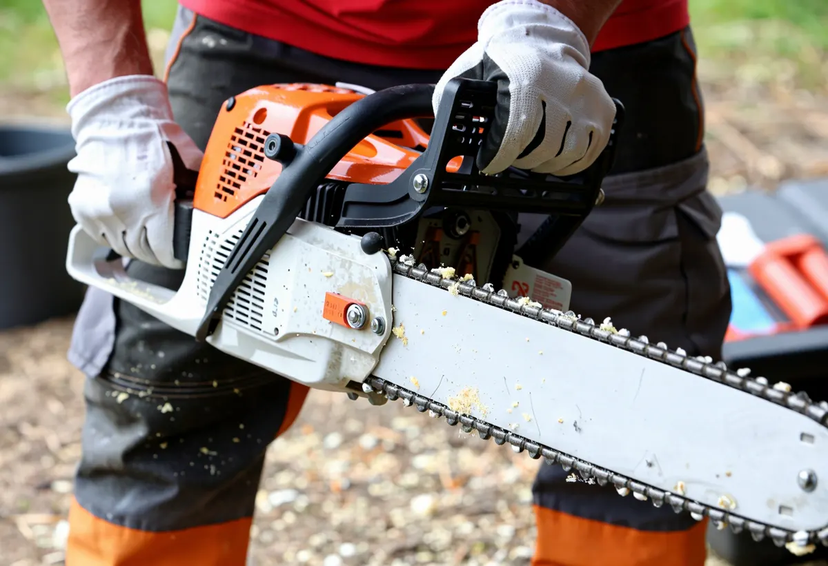 Close up of gloved hands holding a professional chainsaw